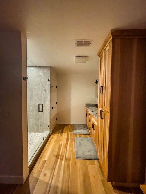 a newly renovated bathroom with wooden floors and a modern walk in shower